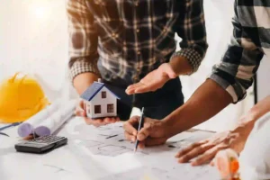 A-scale-model-of-a-house-placed-on-a-table-with-agreement-documents,-symbolizing-the-planning-and-approval-process-for-home-building-grants. 